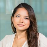A professional Asian businesswoman sitting confidently in a modern office setting.
