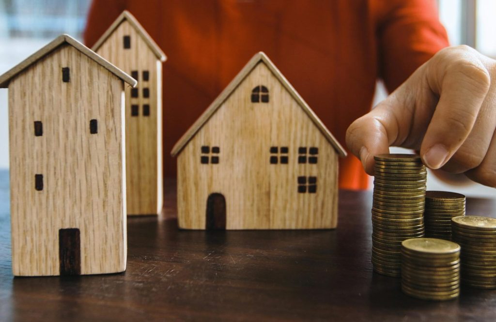 Planning investments with stacked coins and model houses on a table.